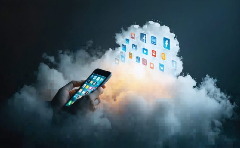 A smartphone surrounded by a shadowy cloud with symbols of anxiety, depression, and loneliness, representing the impact of social media on children's mental health.