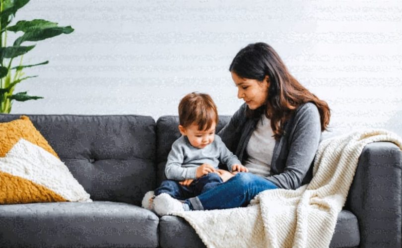 A caring parent comforts their anxious child in a nurturing home environment, surrounded by comforting elements like a soft blanket and warm lighting, symbolizing a supportive atmosphere.