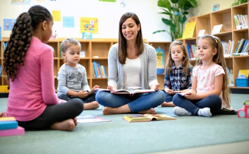 A diverse group of students practicing mindfulness exercises in a well-lit classroom with a cozy reading corner, soft lighting, and a quiet space for stress relief.