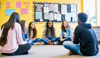 Diverse group of students engaging in a supportive circle discussion with a counselor in a school setting, illustrating a successful school mental health program.