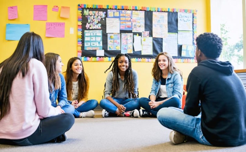 Diverse group of students engaging in a supportive circle discussion with a counselor in a school setting, illustrating a successful school mental health program.