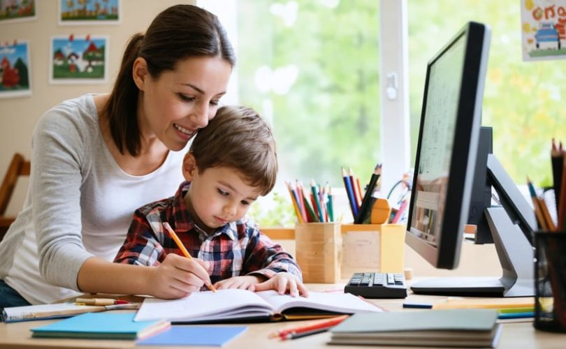 Parent and child working together on homework at a kitchen table, surrounded by books and educational materials, symbolizing active family engagement in education.