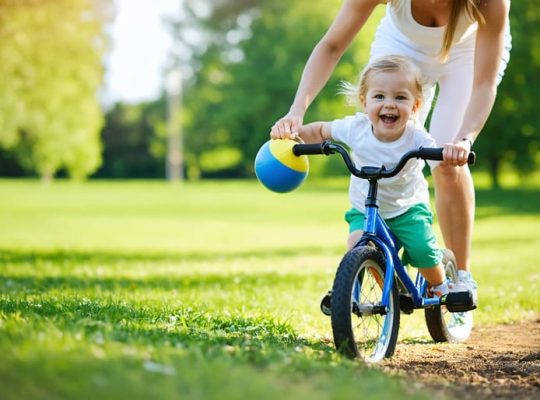 A parent and child smiling while playing together in a park, illustrating the joy and mental health benefits of exercise.