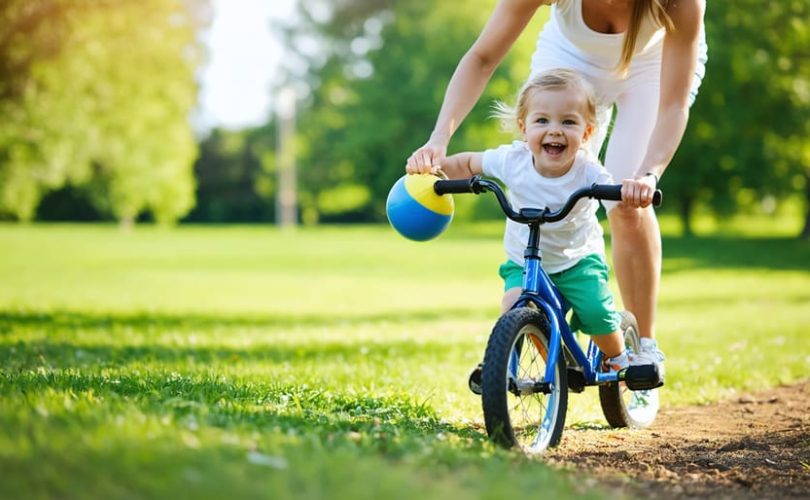 A parent and child smiling while playing together in a park, illustrating the joy and mental health benefits of exercise.